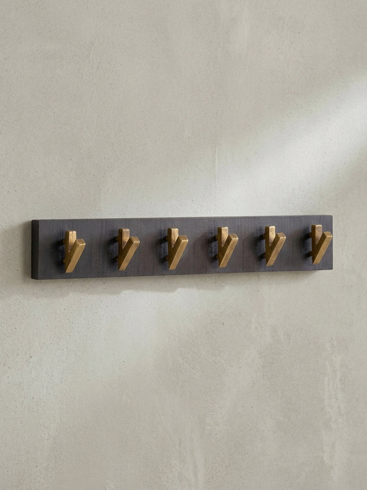 Schräge Ansicht der 60 cm breiten Hakenleiste, die die Tiefe der goldenen Metallhaken vor der schwarzen Holzleiste zeigt._