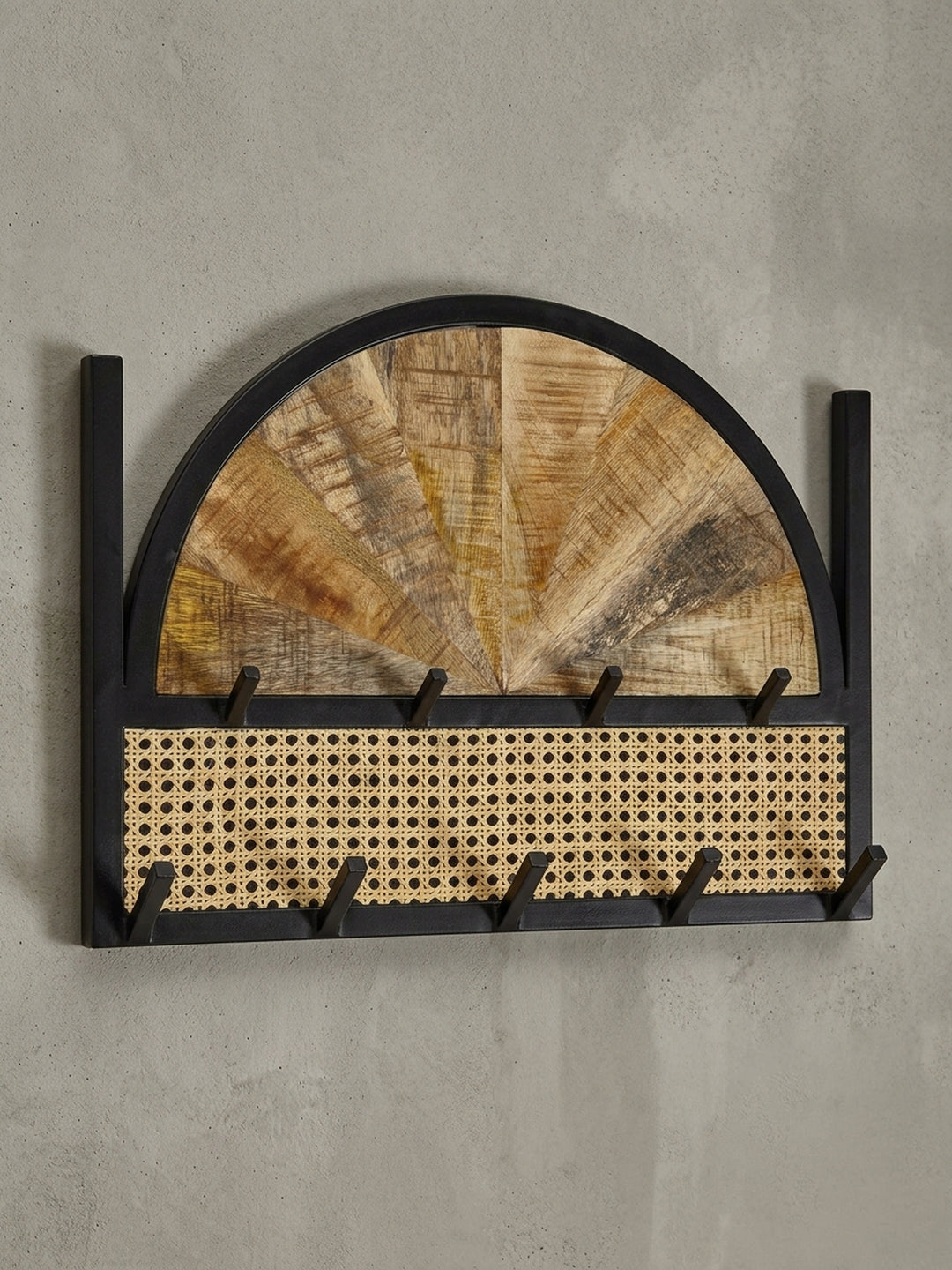 Schräge 3/4-Ansicht des Garderobenpaneels, die die Tiefe der Haken und den Materialmix aus Holz, Rattan und Metall zeigt._