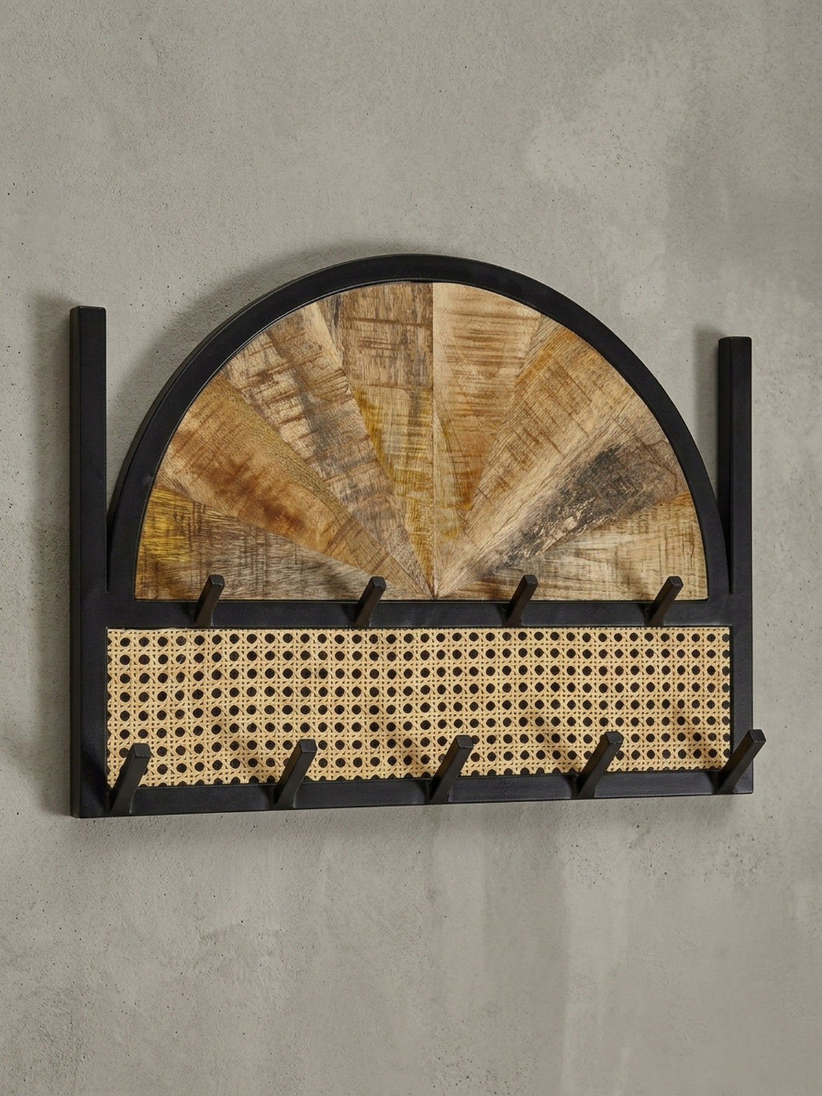 Schräge 3/4-Ansicht des Garderobenpaneels, die die Tiefe der Haken und den Materialmix aus Holz, Rattan und Metall zeigt.