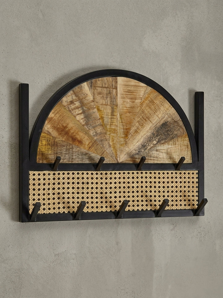 Schräge 3/4-Ansicht des Garderobenpaneels, die die Tiefe der Haken und den Materialmix aus Holz, Rattan und Metall zeigt._