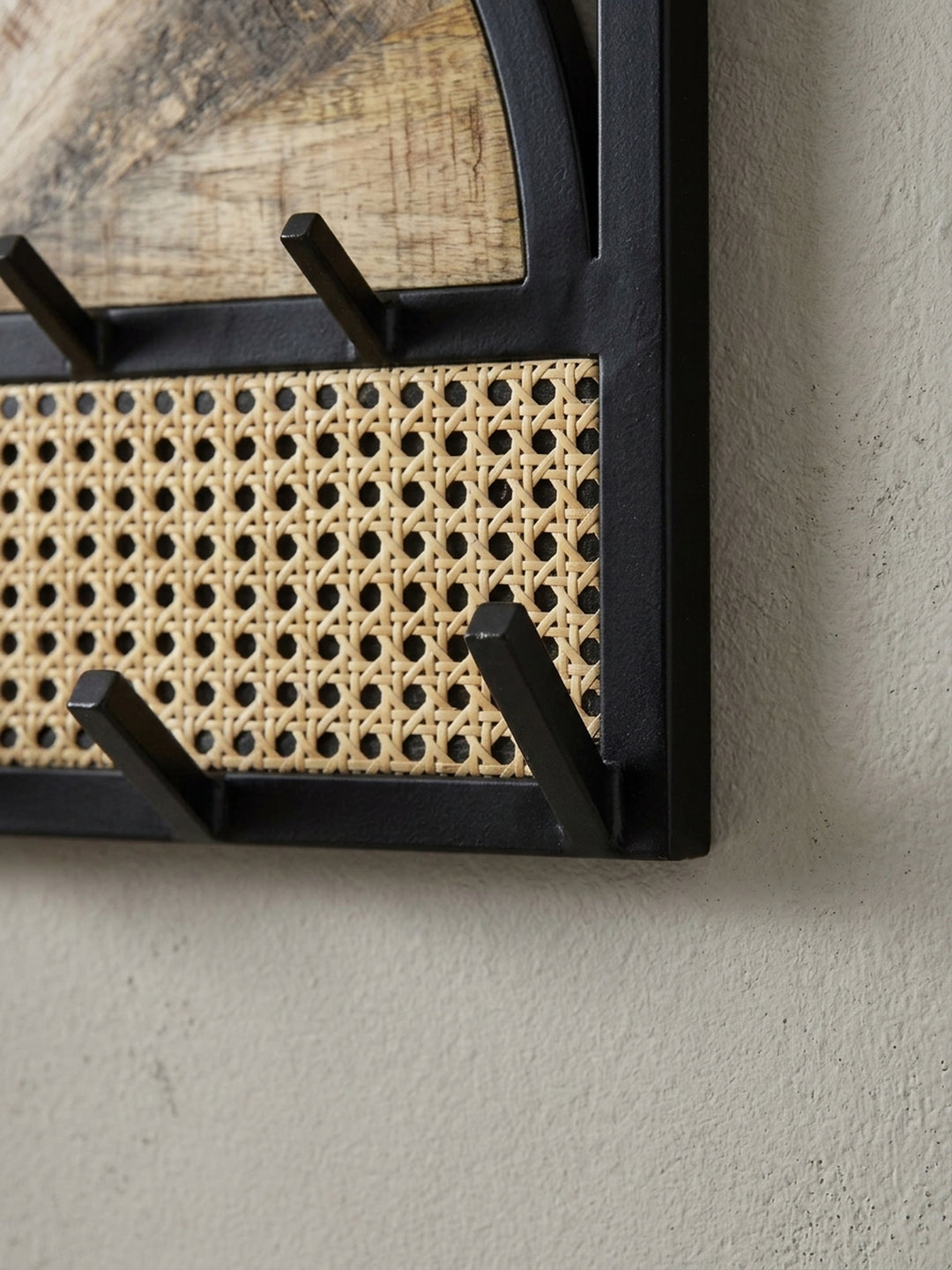 Detailaufnahme eines der schwarzen, pulverbeschichteten Kleiderhaken vor dem hellen Hintergrund des Wiener Geflechts._