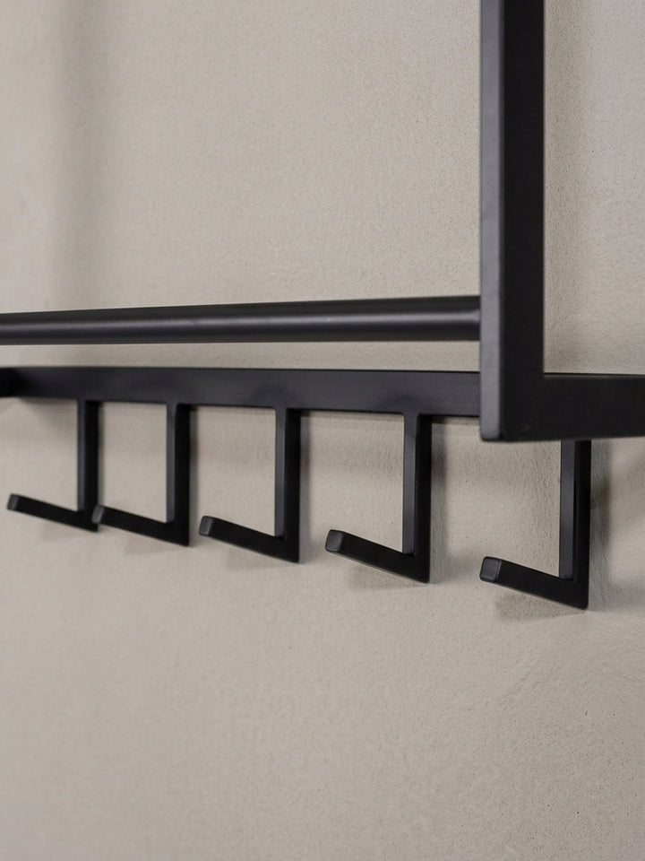 Alternative Perspektive der Wandgarderobe, die das Zusammenspiel der Gitterablage für Hüte und der darunter liegenden Kleiderstange für Bügel betont._