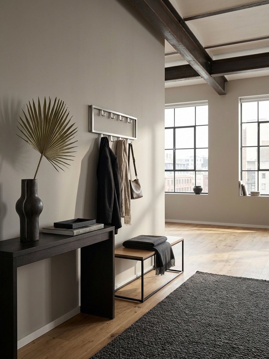 Moderne Wandgarderobe aus silbernem Stahl in einem minimalistischen Flur, montiert über einer Eichenholzbank mit einem Kaschmirschal an einem der neun Haken._