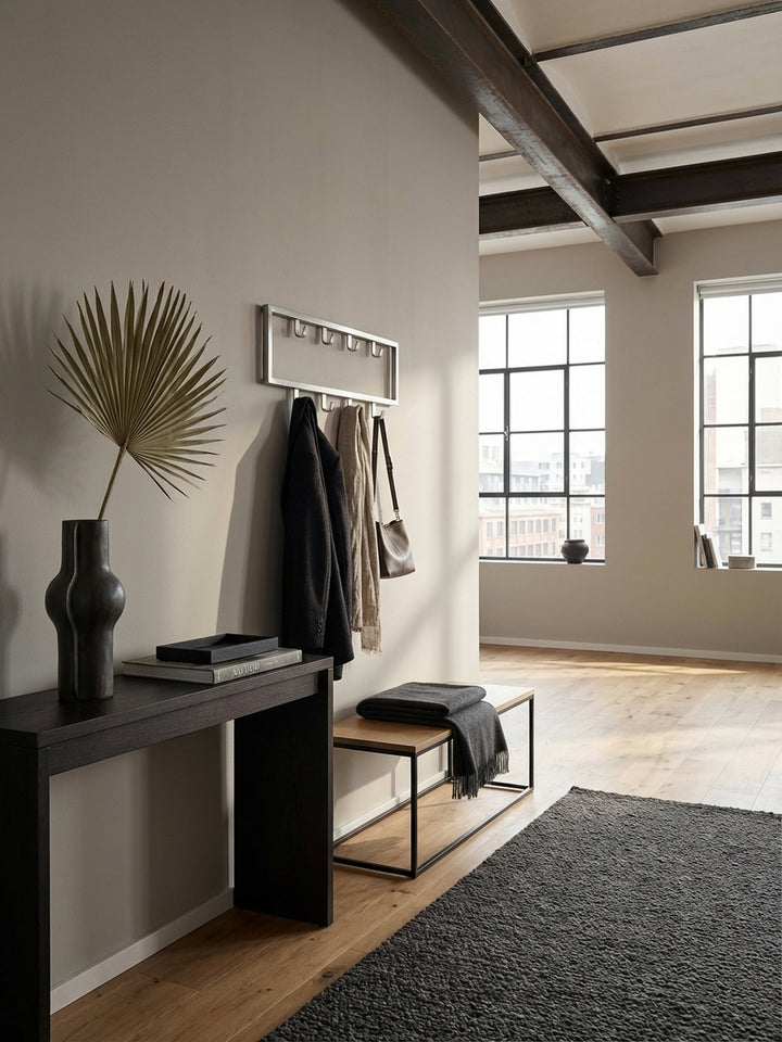 Moderne Wandgarderobe aus silbernem Stahl in einem minimalistischen Flur, montiert über einer Eichenholzbank mit einem Kaschmirschal an einem der neun Haken._