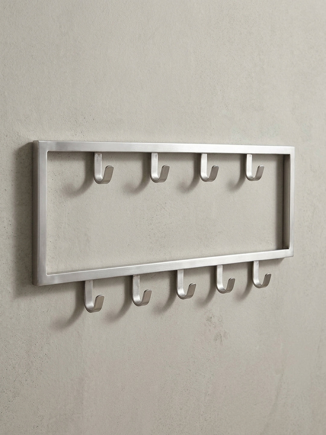 Schräge 3/4-Ansicht der silbernen Flurgarderobe aus Metall, die die Tiefe von 4 cm und die robuste Form der neun Haken für Jacken und Mäntel hervorhebt._