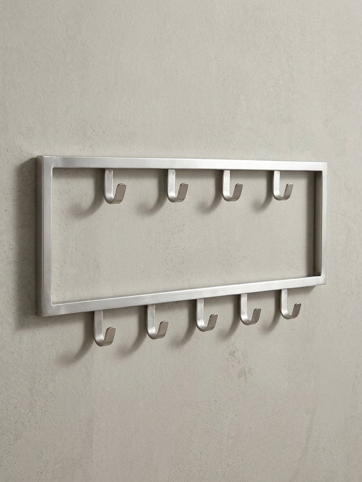 Schräge 3/4-Ansicht der silbernen Flurgarderobe aus Metall, die die Tiefe von 4 cm und die robuste Form der neun Haken für Jacken und Mäntel hervorhebt._