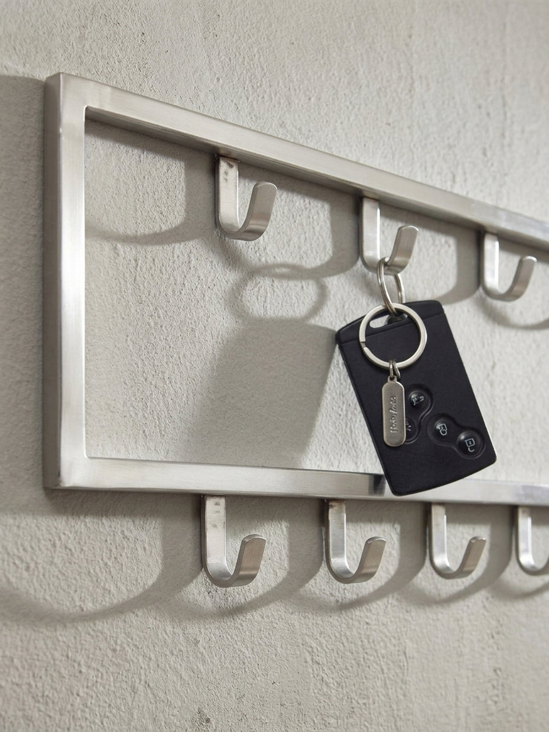 Nahaufnahme eines einzelnen Kleiderhakens der silbernen Wandgarderobe, der die saubere Schweißnaht und die hochwertige Verarbeitung des matten Stahls demonstriert._