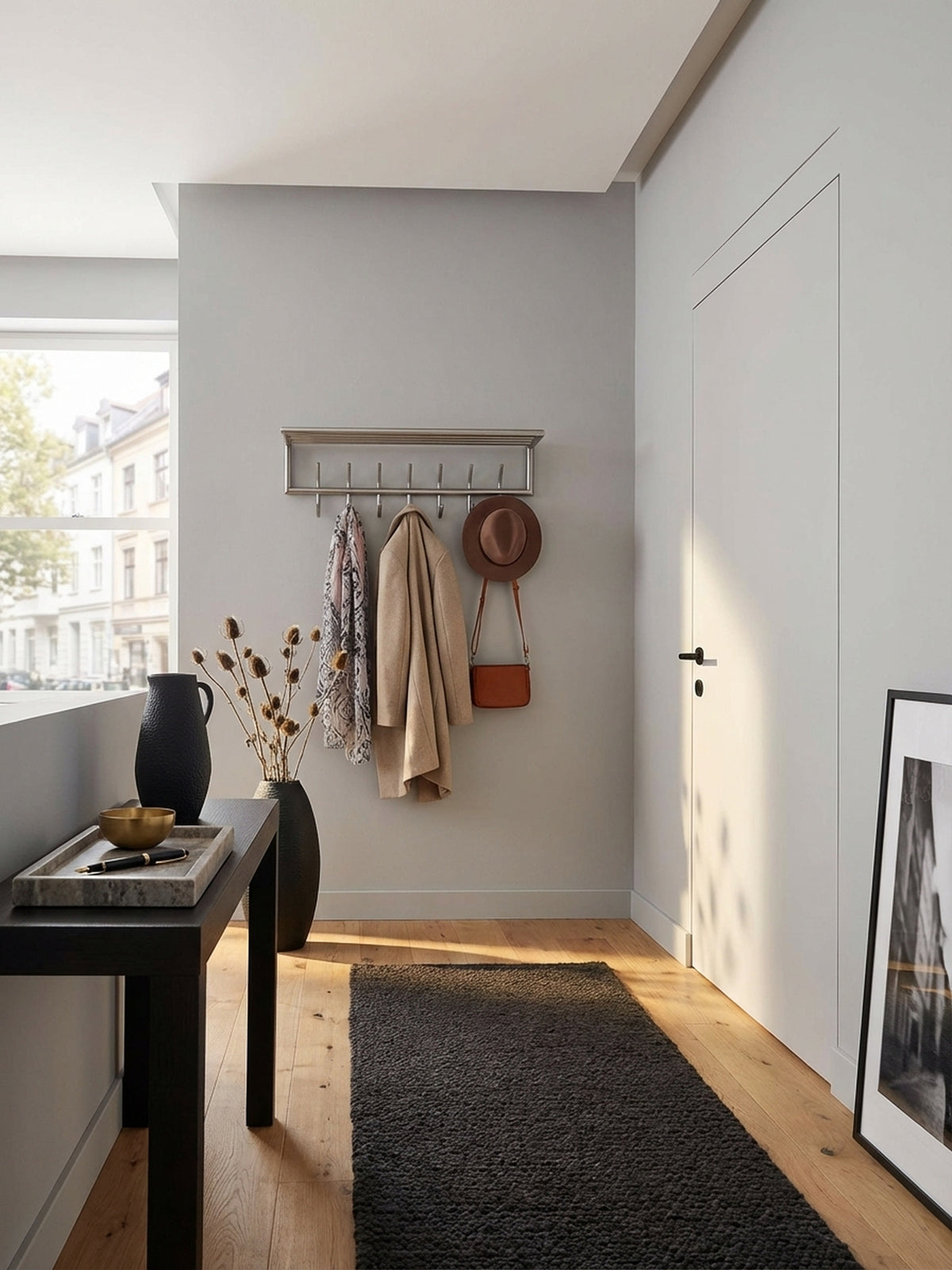 Design Wandgarderobe aus mattem Stahl in einem hellen, aufgeräumten Flur, die praktische Hutablage ist mit einem Korb und Hut dekoriert und bietet viel Stauraum.