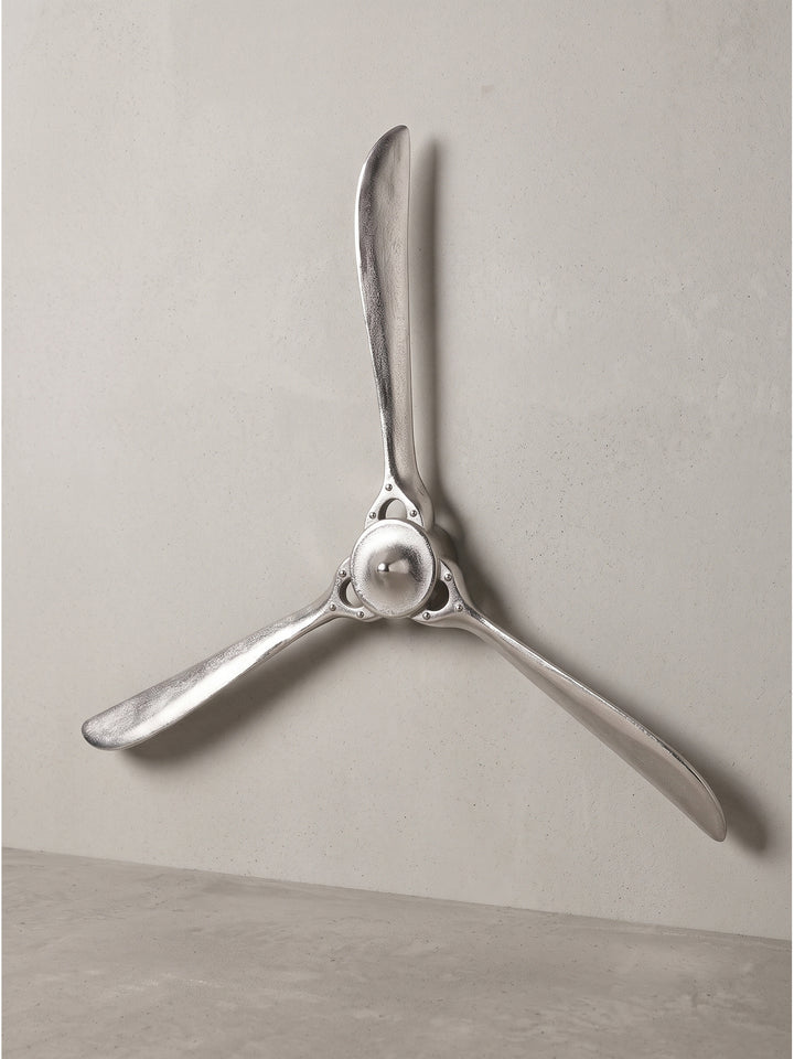 Frontale Perspektive des silbernen Flugzeugpropellers vor dunklem Hintergrund, welche die detaillierte Nabe mit Nietenoptik hervorhebt._