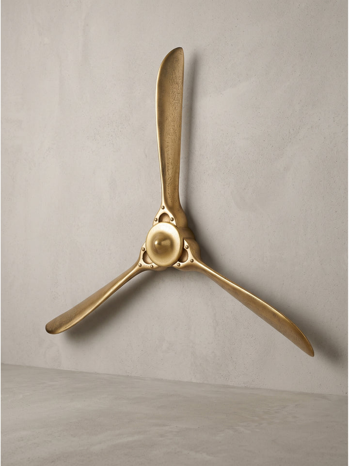 Deko Propeller aus gold lackiertem Aluminium mit drei Flügeln 85x85 cm in Frontalansicht vor weißem Hintergrund._