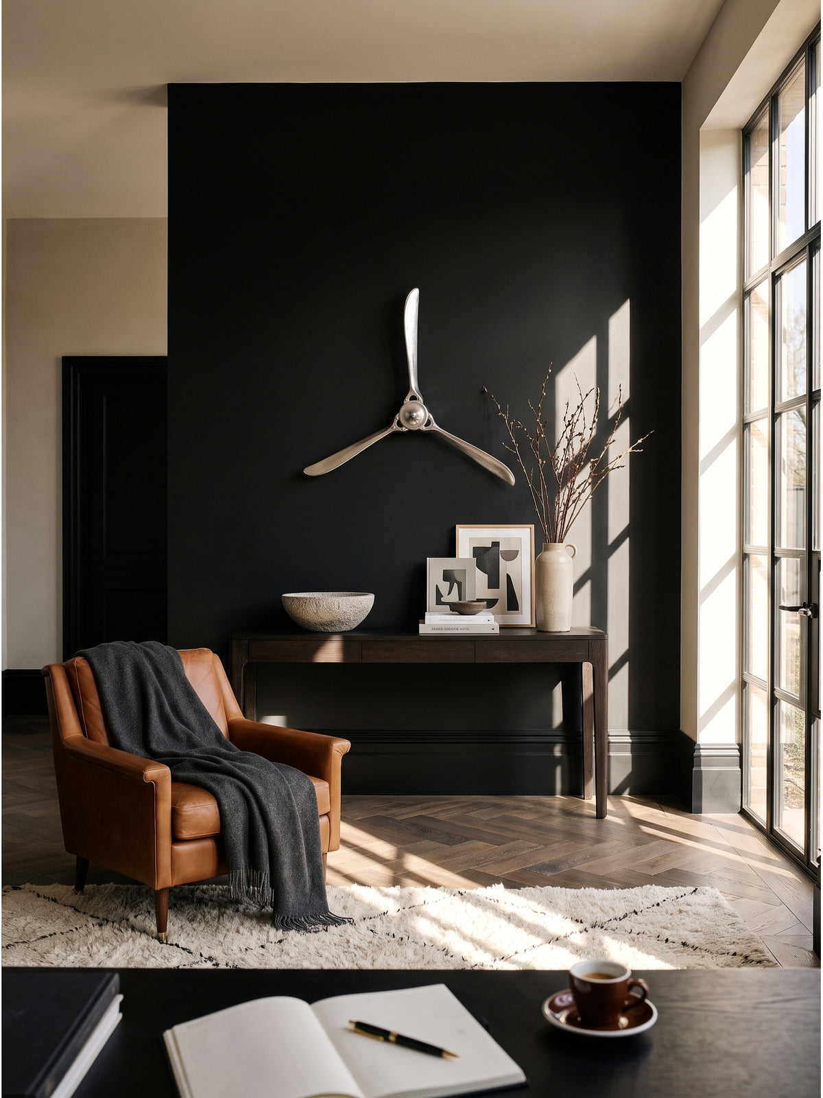 Silberner Flugzeugpropeller aus vernickeltem Aluminium als Wanddekoration im luxuriösen Home Office vor einer schwarzen Akzentwand.