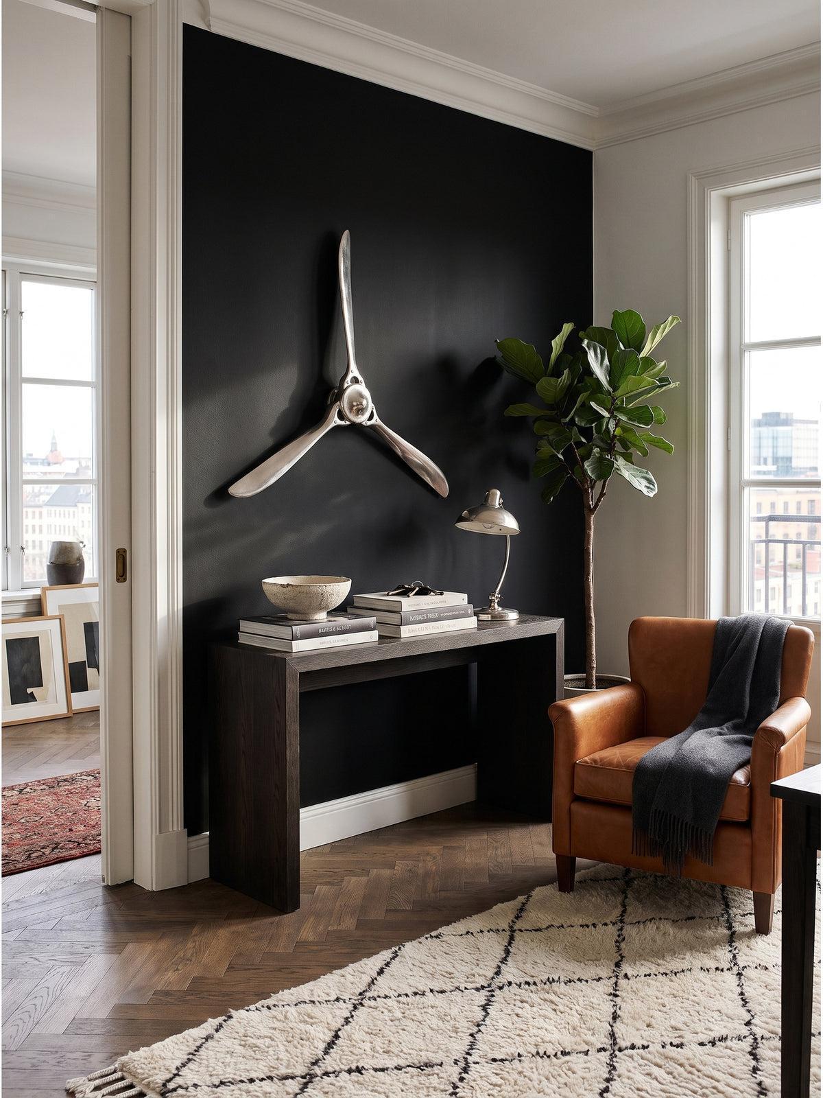Silberner Wandpropeller aus Aluminium im Ensemble mit einem cognacfarbenen Ledersessel und einer schwarzen Stahl-Stehleuchte im Raum.