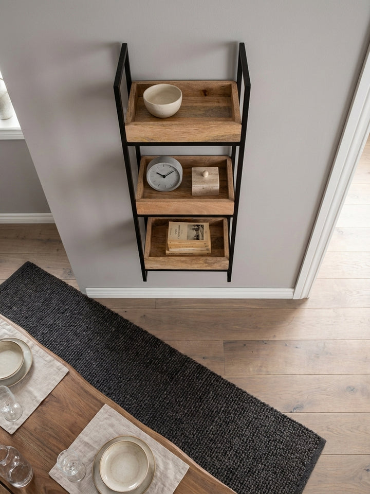 Draufsicht auf ein schmales Hängeregal mit drei Tablett-Ablagen aus Mangoholz, das in einer Nische im Home Office für Ordnung und Design sorgt._