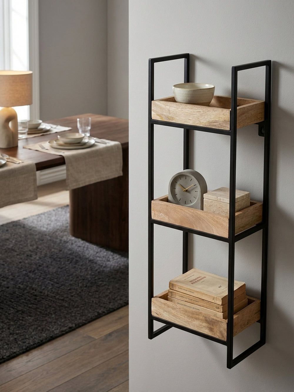 Dekoratives Tablettregal aus Holz und Metall, auf dem eine kleine Uhr, ein Keramikgefäß und eine Hängepflanze eine gemütliche Vignette an der Wand bilden._