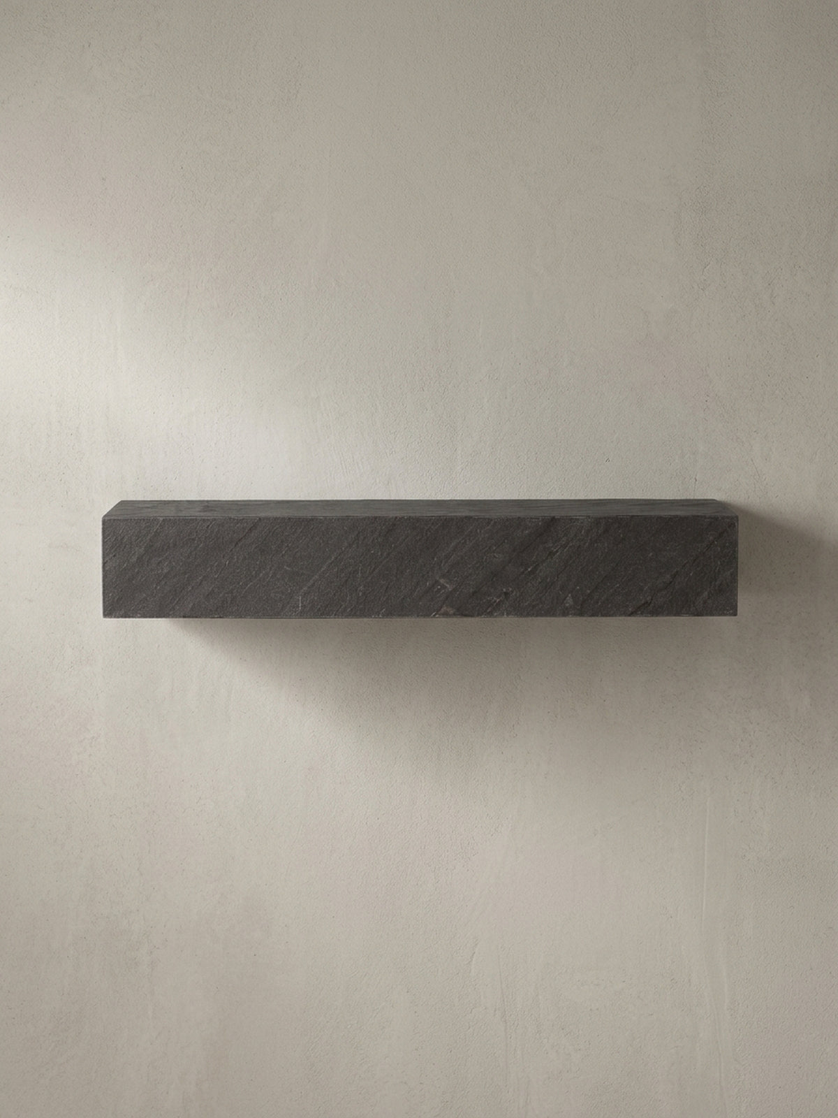 Schrägansicht des rechteckigen Schweberegals in Anthrazit, die seine monolithische, 10 cm hohe Form und die 3D-Struktur betont._