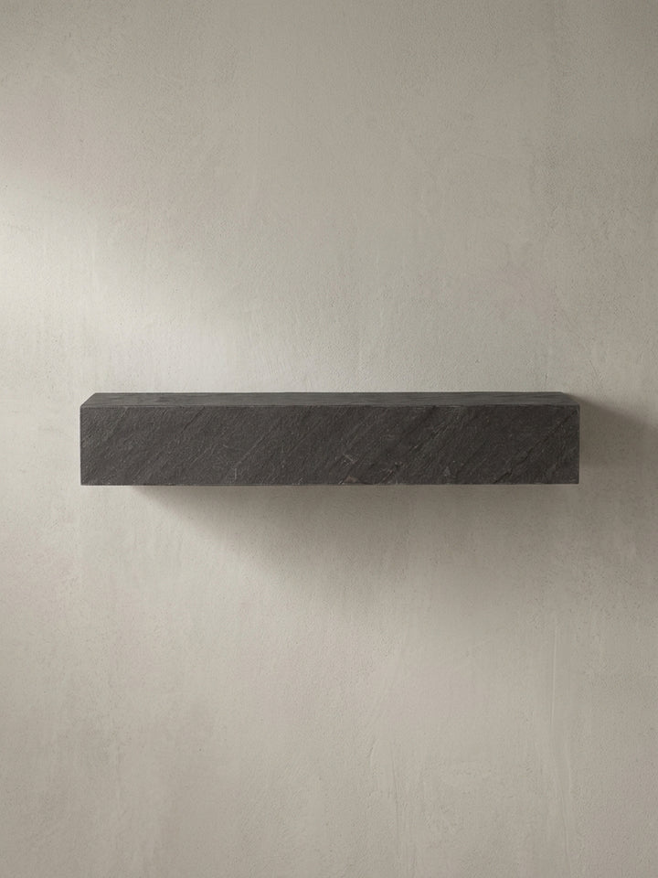 Schrägansicht des rechteckigen Schweberegals in Anthrazit, die seine monolithische, 10 cm hohe Form und die 3D-Struktur betont._