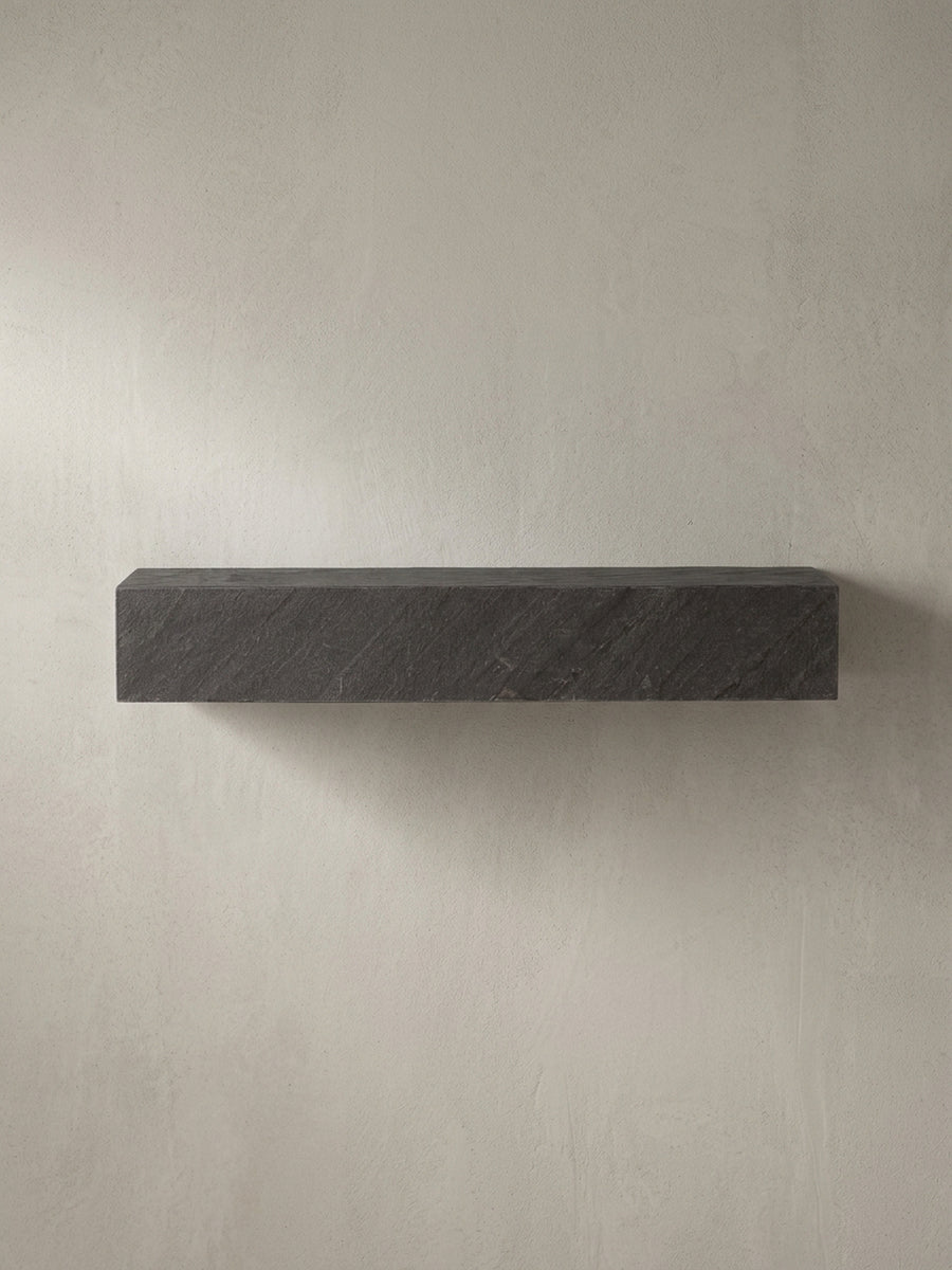 Schrägansicht des rechteckigen Schweberegals in Anthrazit, die seine monolithische, 10 cm hohe Form und die 3D-Struktur betont._