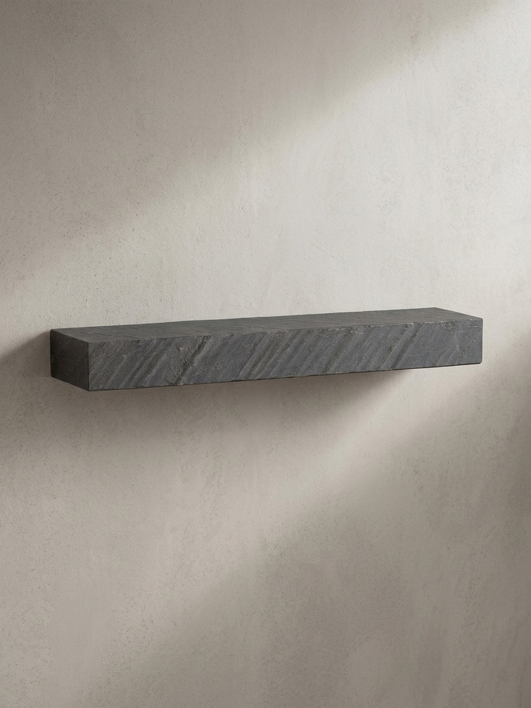 Das massive Hängeregal aus Mangoholz in einer schrägen 3/4-Ansicht, die die Tiefe von 20 cm und die gebrochenen Kanten der Steinoptik hervorhebt._