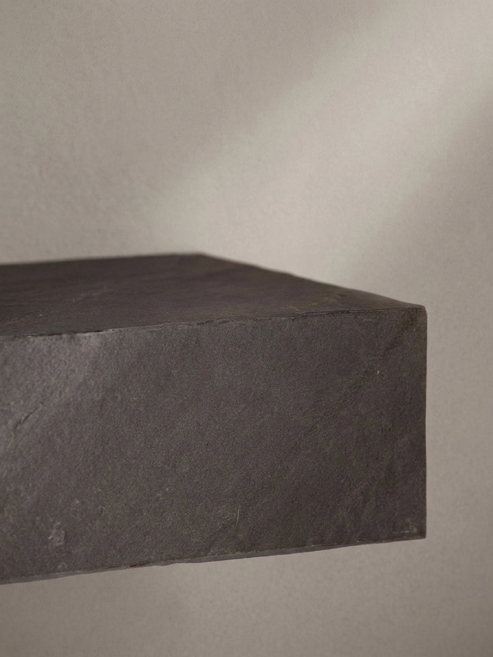 Nahaufnahme der Kantenverarbeitung des Wandregals, dessen Kunststoffoberfläche die charakteristischen Unregelmäßigkeiten von Stein imitiert._