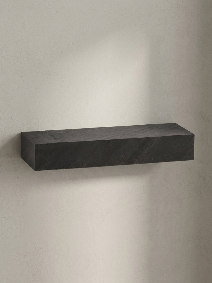 Alternative Perspektive auf das anthrazitfarbene Design-Regal, die das Spiel von Licht und Schatten auf der texturierten Oberfläche einfängt._