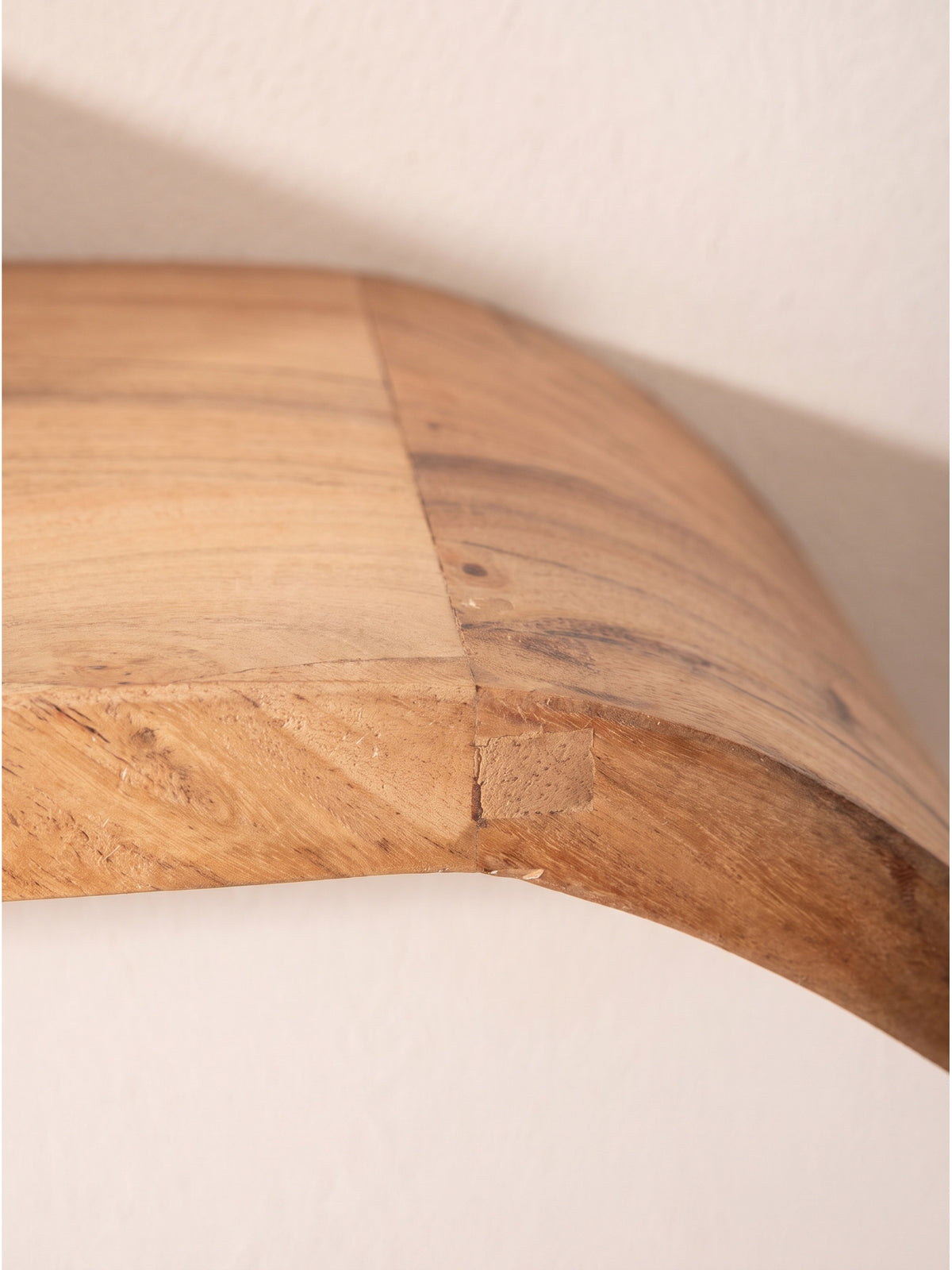 Nahaufnahme der warmen Maserung und der fließenden Holzkurve des handgefertigten Schweberegals aus massivem Mangoholz_