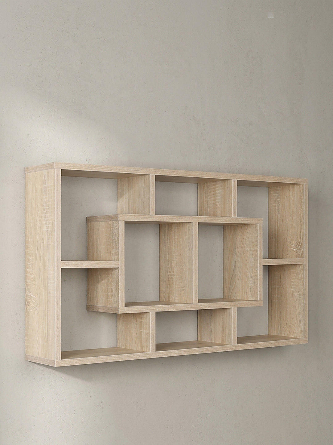 Frontalansicht des leeren Wandregals 85x47x16 cm mit ineinandergreifenden offenen Fächern in heller Holzoptik vor einem neutralen Hintergrund_
