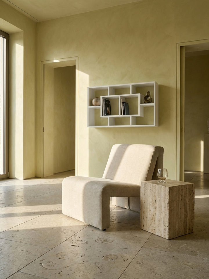 Geometrisches Wandregal aus weißem MDF im minimalistischen Wohnzimmer an einer handverputzten Wand über einem Leinen-Sessel_