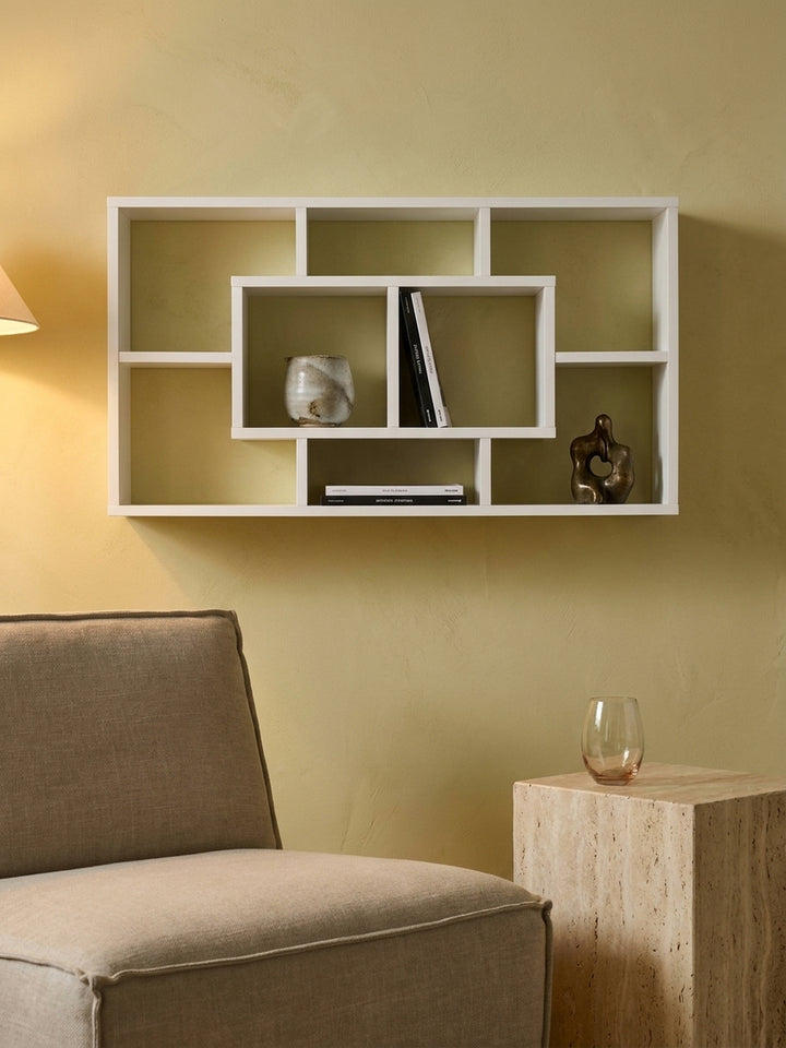 Modernes offenes Holzregal in Weiß dekoriert mit einer Bronzeskulptur und schwarzen Bildbänden im eleganten Arbeitszimmer_