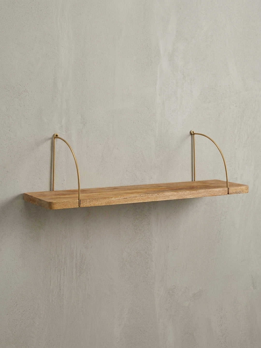 Freigestelltes Wandregal 60x25x22 cm, frontale Ansicht des massiven Mangoholzbretts und der elegant geschwungenen, goldfarbenen Halterungen._