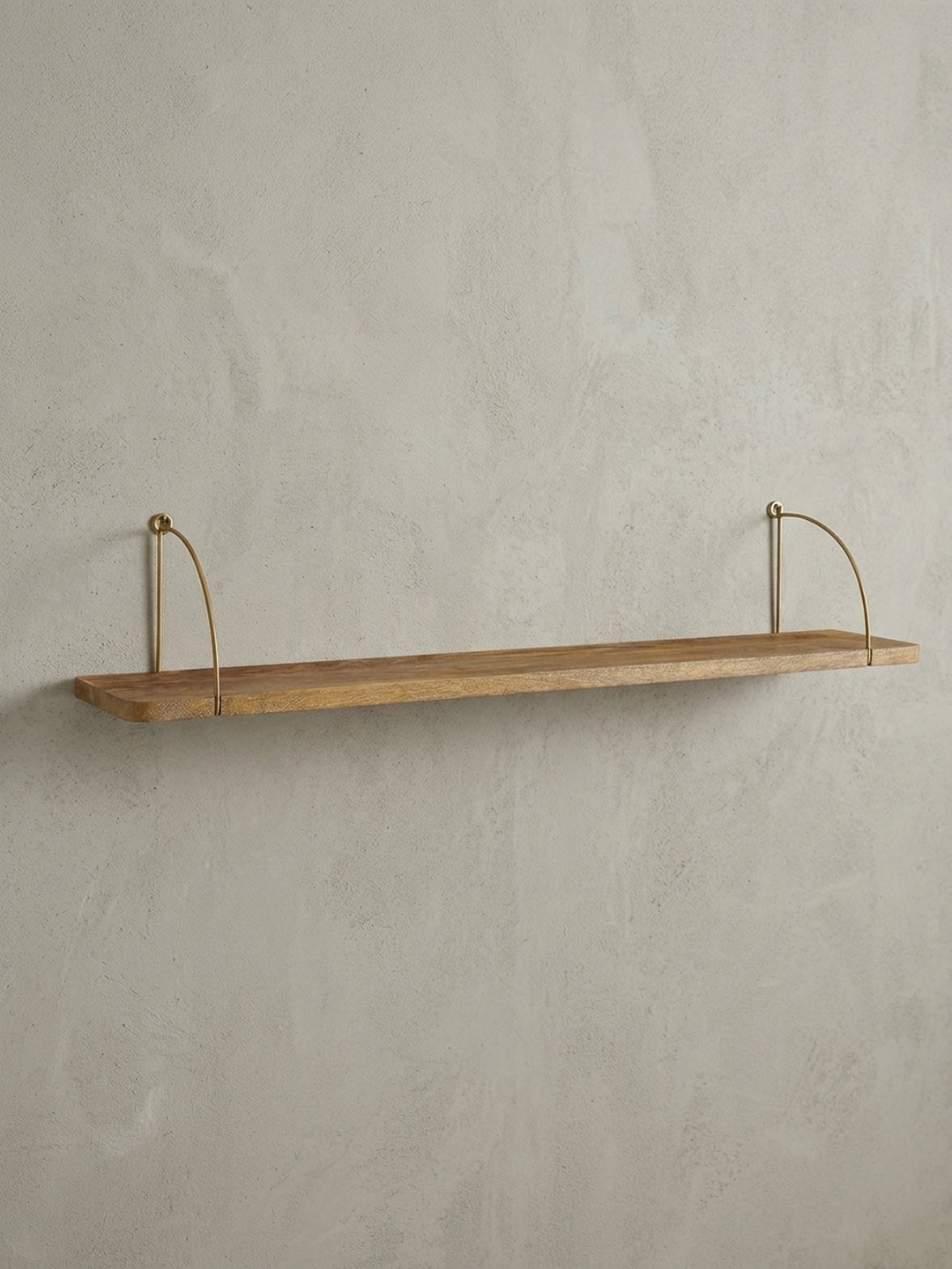 Frontansicht des 100 cm breiten Wandregals aus Mangoholz mit elegant geschwungenen, goldfarbenen Metallhalterungen auf weißem Hintergrund._