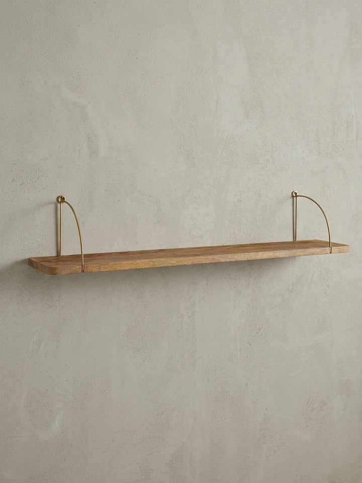 Frontansicht des 100 cm breiten Wandregals aus Mangoholz mit elegant geschwungenen, goldfarbenen Metallhalterungen auf weißem Hintergrund._