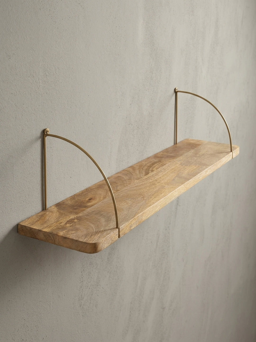 Detailaufnahme einer der goldfarbenen Halterungen des Wandregals, die durch das massive Mangoholz geführt wird und einen Hauch von Industrial-Chic verleiht._