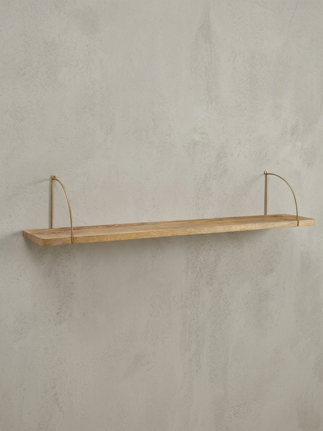 Industrial Schweberegal in der 3/4-Ansicht, die Tiefe der 22 cm Ablagefläche aus Mangoholz und die filigrane Konstruktion der goldenen Halterungen zeigt._