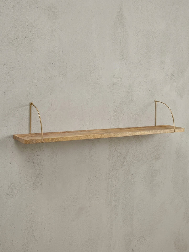 Industrial Schweberegal in der 3/4-Ansicht, die Tiefe der 22 cm Ablagefläche aus Mangoholz und die filigrane Konstruktion der goldenen Halterungen zeigt._