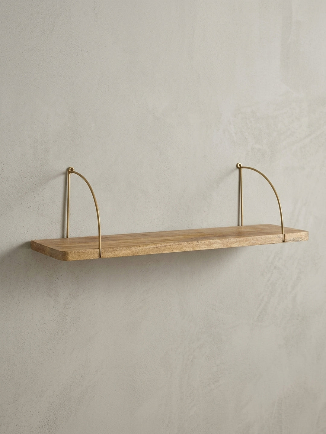 Design Schweberegal in der 3/4-Ansicht, die das Zusammenspiel von warmem Mangoholz und den filigranen Metallbügeln in Gold unterstreicht._