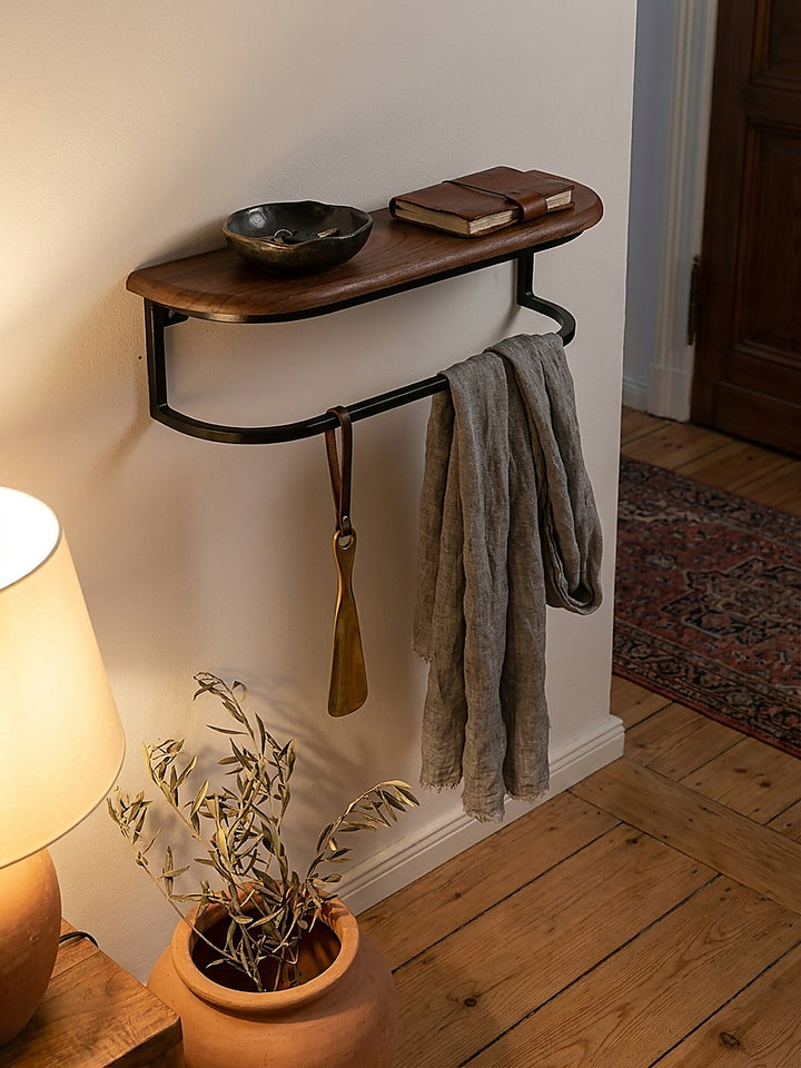 Ein kleines Schweberegal im Flur bietet Platz für Schlüssel und ein Notizbuch neben einer warm strahlenden Wandlampe._