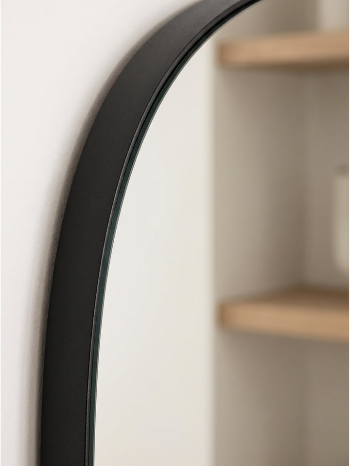 Nahaufnahme des pulverbeschichteten schwarzen Eisenrahmens und der klaren Glasfläche des asymmetrischen Designspiegels._