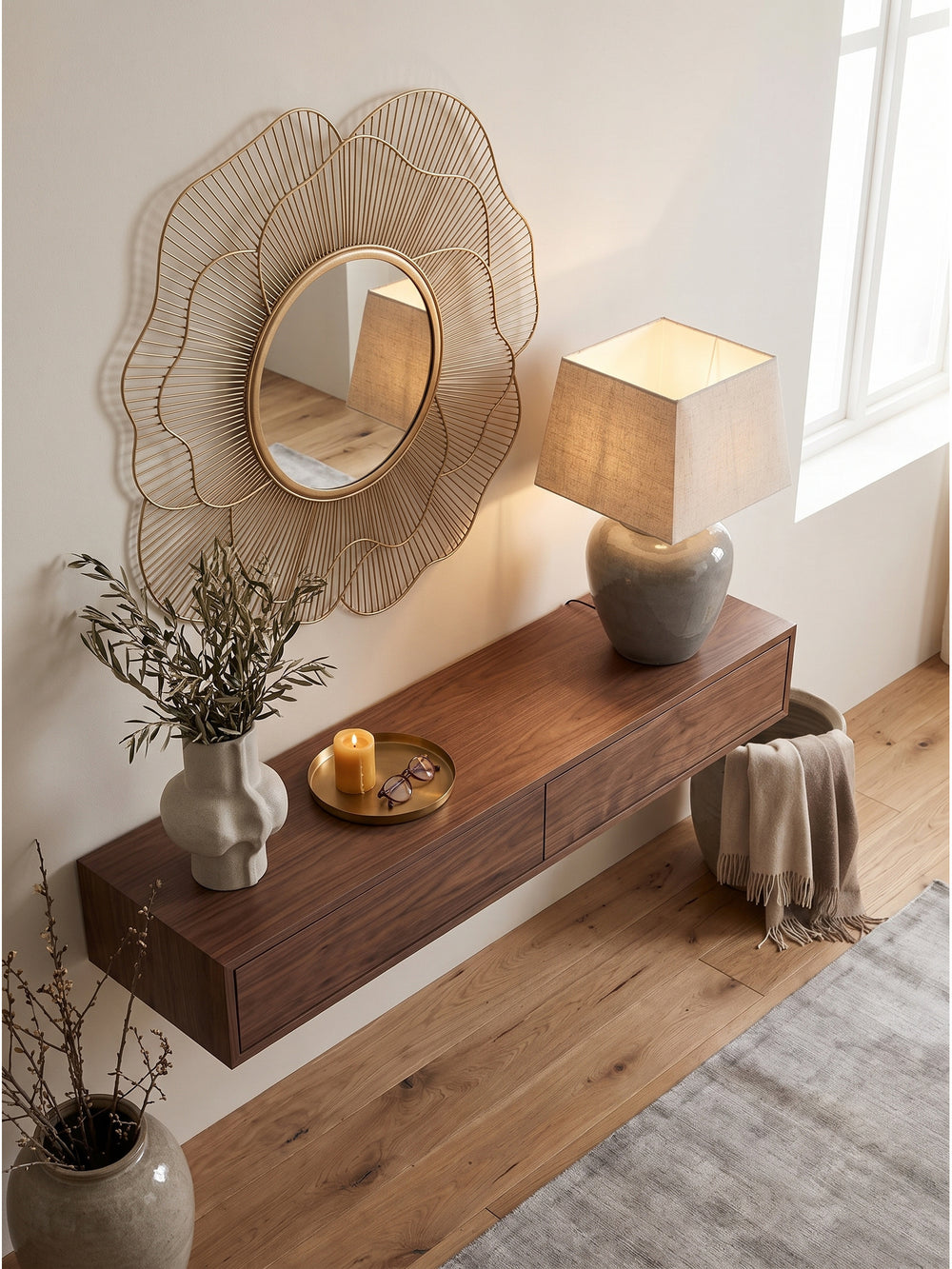 Blick von oben auf den goldenen Metall-Hängespiegel im floralen Design über einem Massivholztisch auf edlem Eichenparkett._