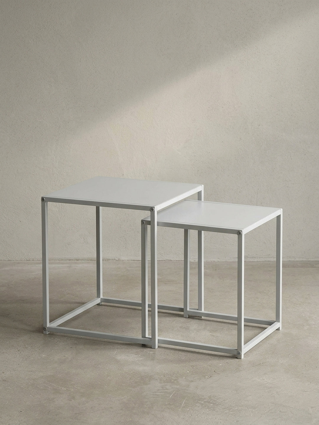 Frontale Ansicht der geometrischen Satztische eckig aus mattweißem Stahl auf neutralem Hintergrund, entworfen für klare und minimalistische Inneneinrichtungen._