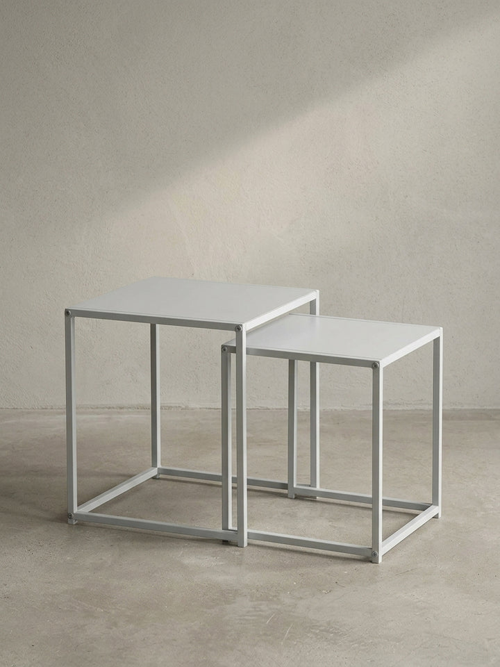 Frontale Ansicht der geometrischen Satztische eckig aus mattweißem Stahl auf neutralem Hintergrund, entworfen für klare und minimalistische Inneneinrichtungen._