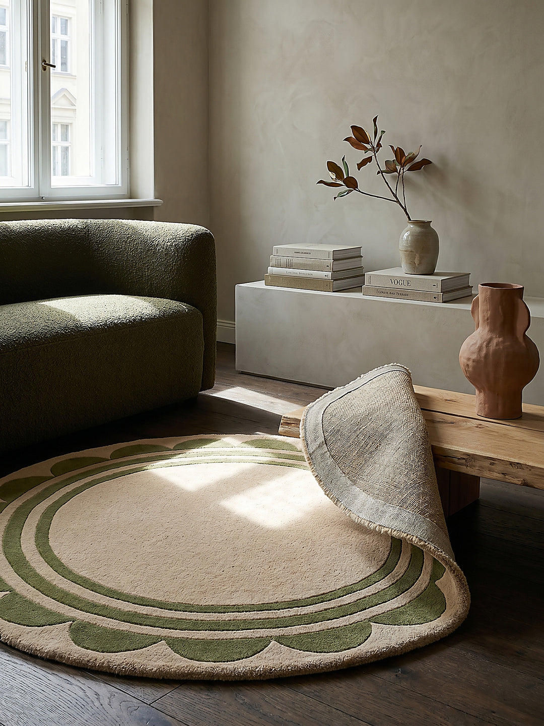 Teppich Grün-Beige rund Editorial Interior als Designobjekt drapiert hochwertige Wohnaccessoires_